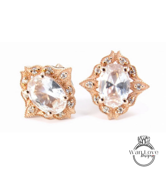 two ornate earrings with large, clear gemstones set in a decorative gold frame.