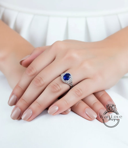 A close-up image of a person's hands wearing a ring with a large blue gemstone.