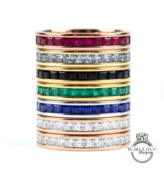 A stack of rings with various colored gemstones set in gold bands.