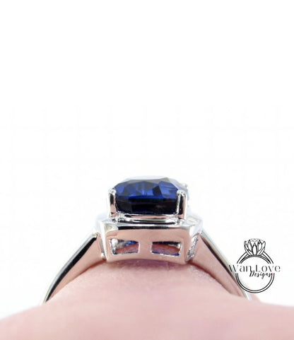 A close-up view of a silver ring with a large blue gemstone, likely a sapphire, set in the center.