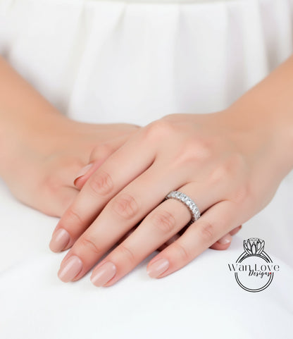 A close-up of a person's hands wearing a diamond ring, with a white background.