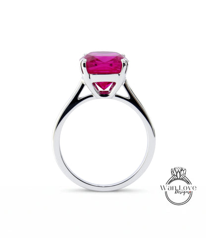 A silver ring with a large, bright pink gemstone set in the center.