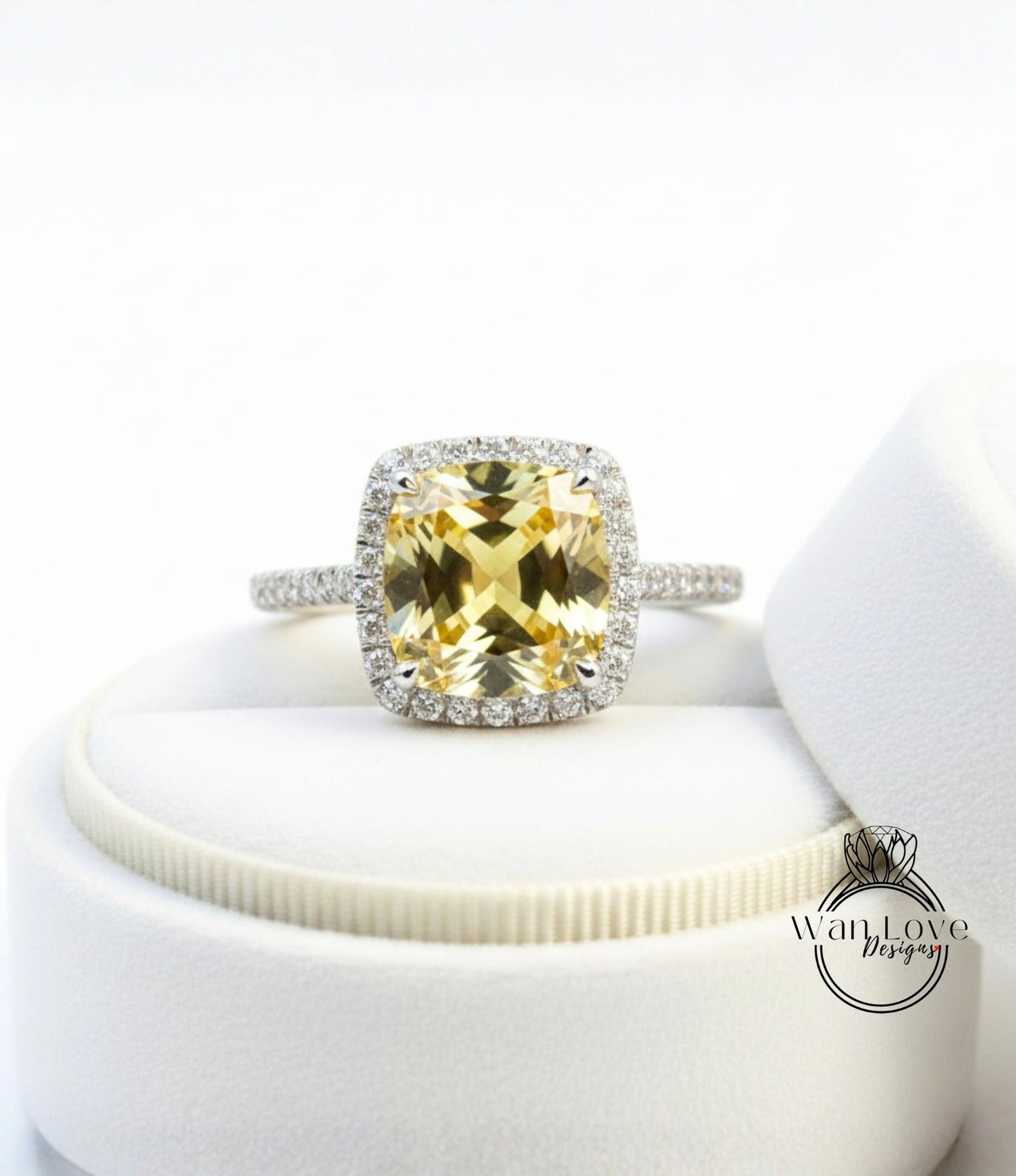 A yellow gemstone engagement ring with a halo of diamonds, displayed on a white ring box.