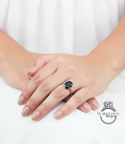 A close-up of a person's hands wearing a ring with a large black gemstone.