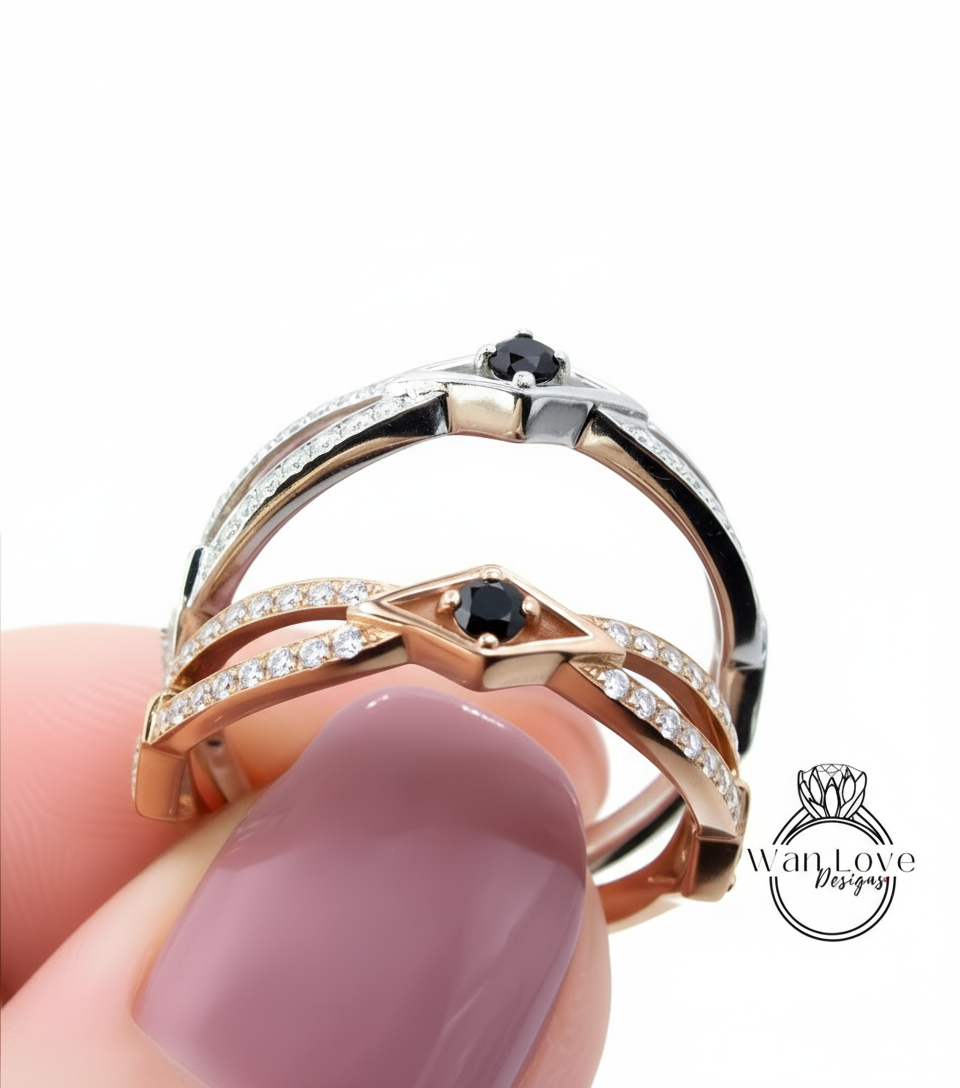 A close-up of a person's hand holding a ring with two diamond-encrusted bands and a black gemstone.