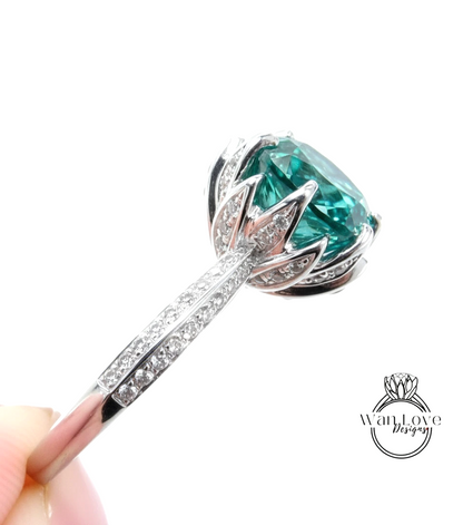 A close-up view of a silver ring with a large, green gemstone set in the center, surrounded by smaller diamonds.