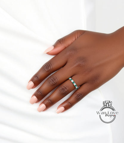 A close-up of a hand wearing a ring with green and white stones.