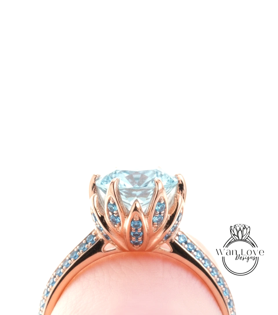A close-up view of a rose gold ring with a large blue gemstone, possibly a diamond, set in a delicate flower-like design.