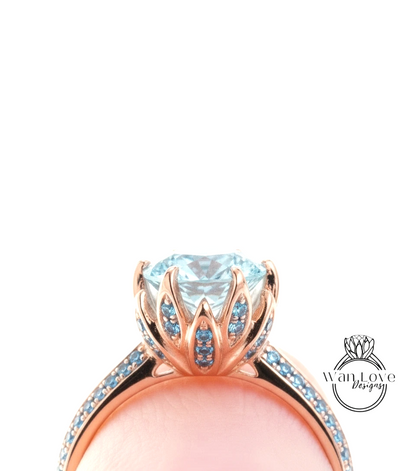 A close-up view of a rose gold ring with a large blue gemstone, possibly a diamond, set in a delicate flower-like design.