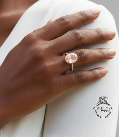 A close-up of a hand wearing a large, round, pink gemstone ring on the ring finger.