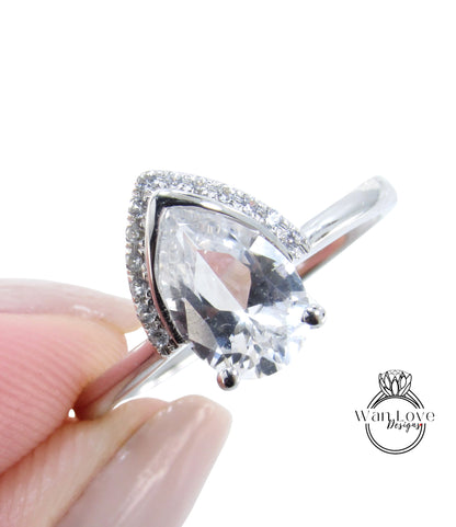 A close-up image of a person's hand holding a diamond ring with a large, clear gemstone.