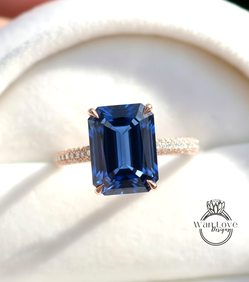 A close-up image of a gold ring with a large blue gemstone, likely an emerald, set in the center.