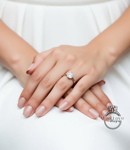 A close-up image of a person's hands with a diamond engagement ring on the ring finger.
