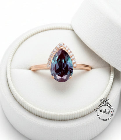 A close-up image of a gold ring with a large, deep purple gemstone set in the center, placed in a white jewelry box.