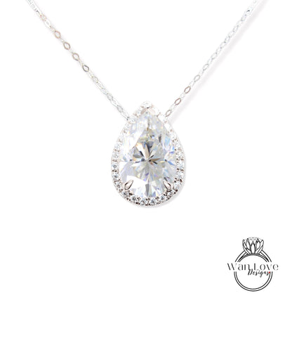 A close-up view of a diamond pendant necklace with a large, clear pear-shaped diamond set in a halo of smaller diamonds.