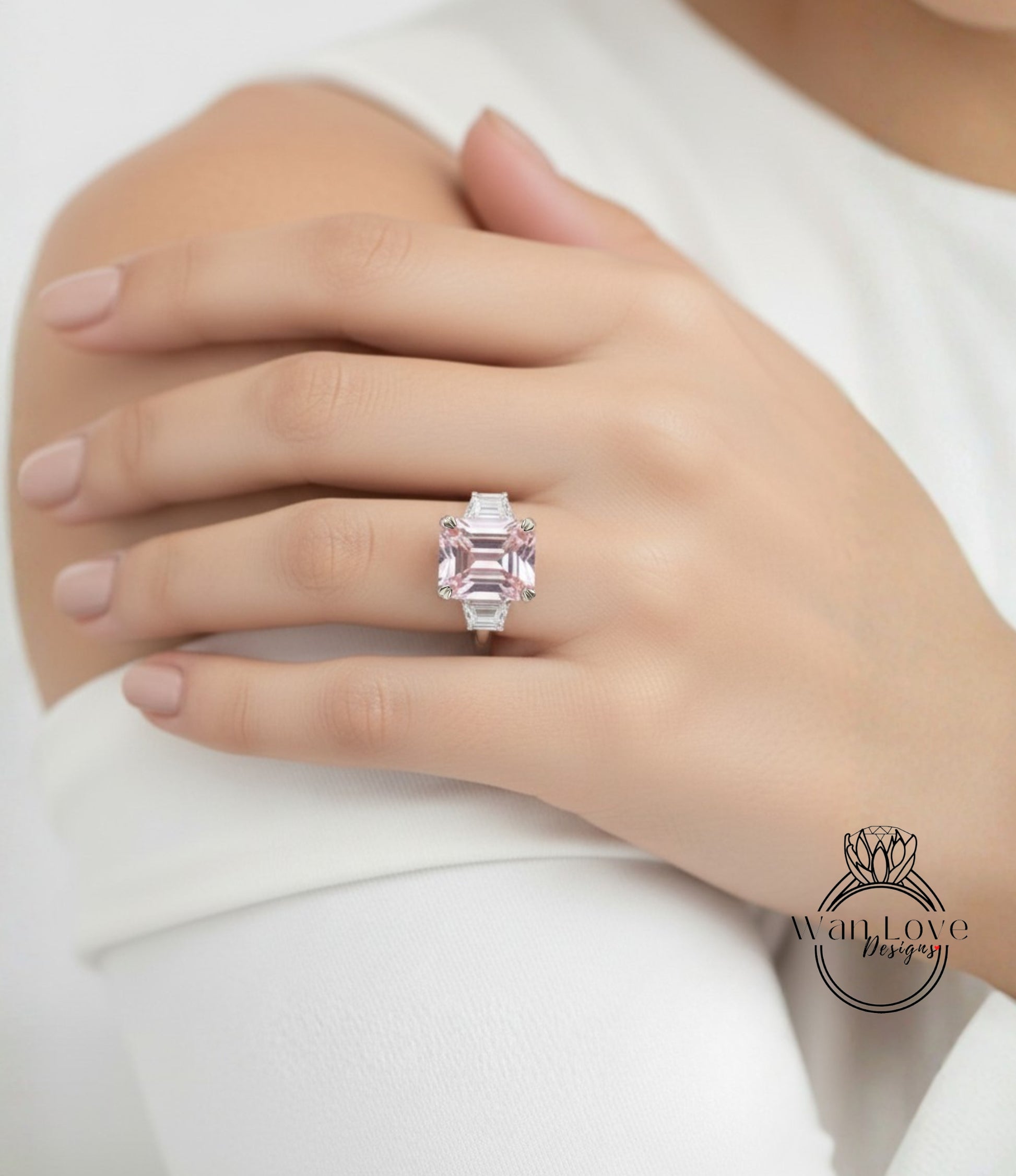 A close-up of a person's hand wearing a large, pink diamond ring on the ring finger.