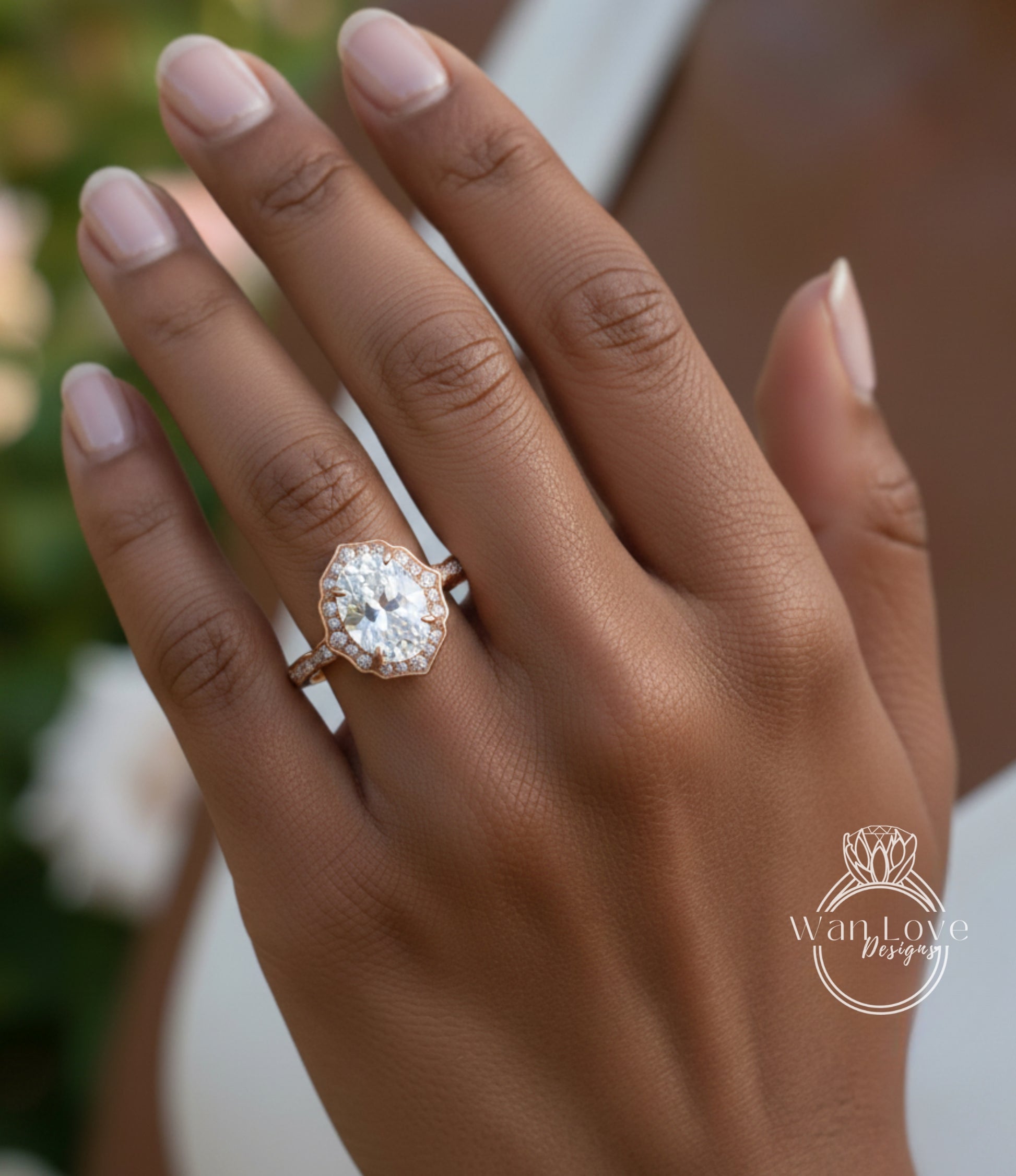 A close-up of a person's hand wearing a large, oval-shaped diamond engagement ring with a halo of smaller diamonds around the center stone.