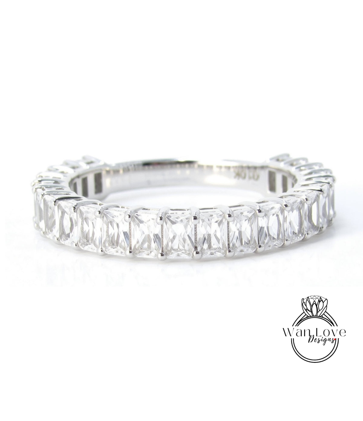 A silver ring with a row of clear gemstones, likely diamonds, set in a band.