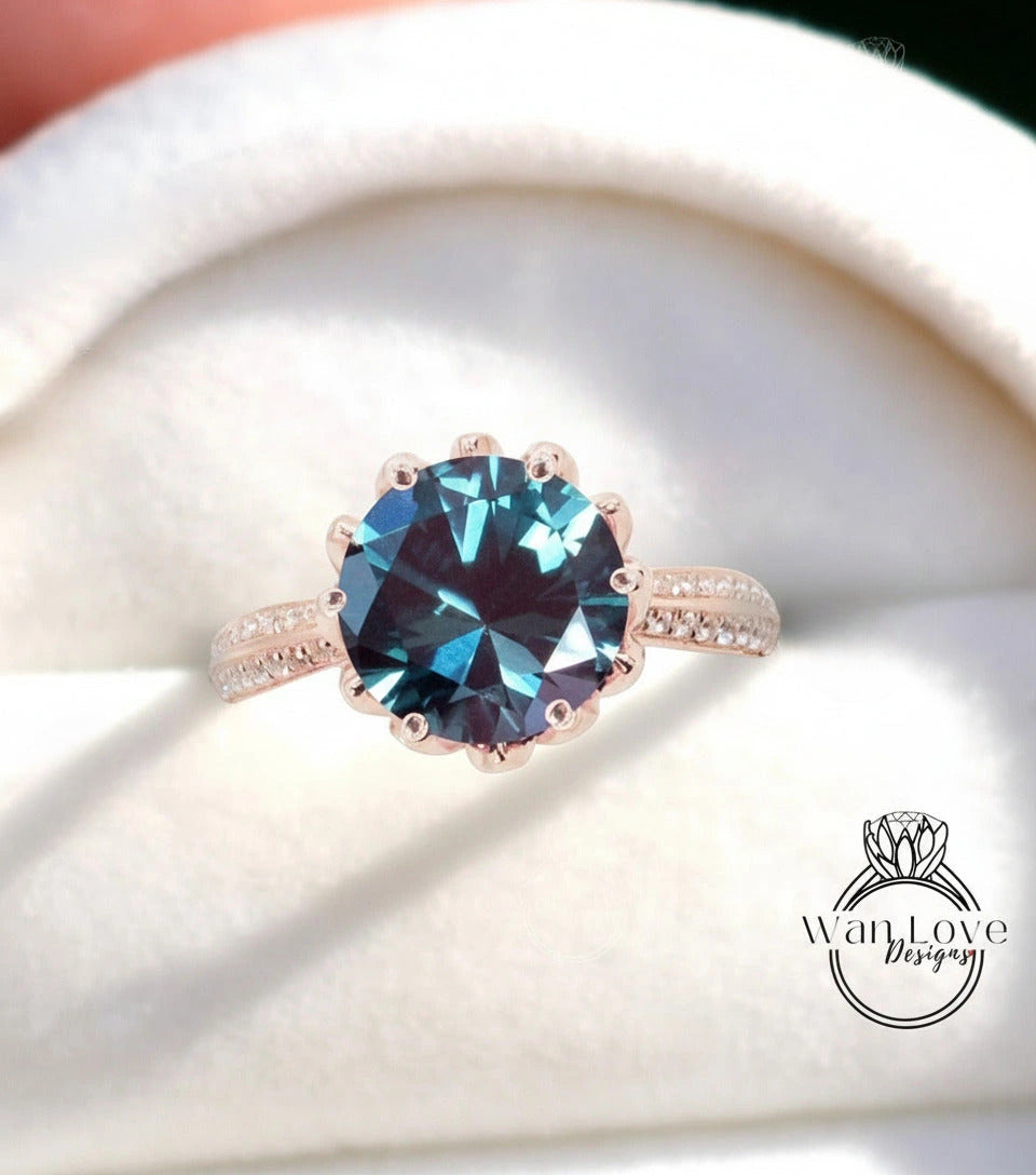 A close-up of a rose gold ring with a large blue gemstone set in the center, placed on a white fabric background.