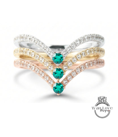 A ring with a diamond band and three green gemstones set in it.