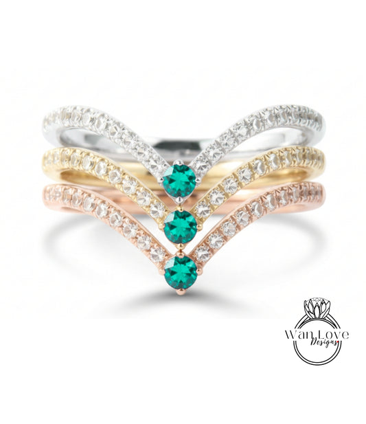 A ring with a diamond band and three green gemstones set in it.