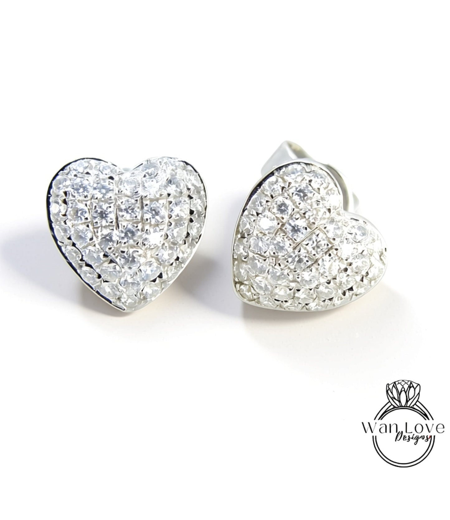 two silver earrings with heart-shaped designs, adorned with numerous small diamonds.