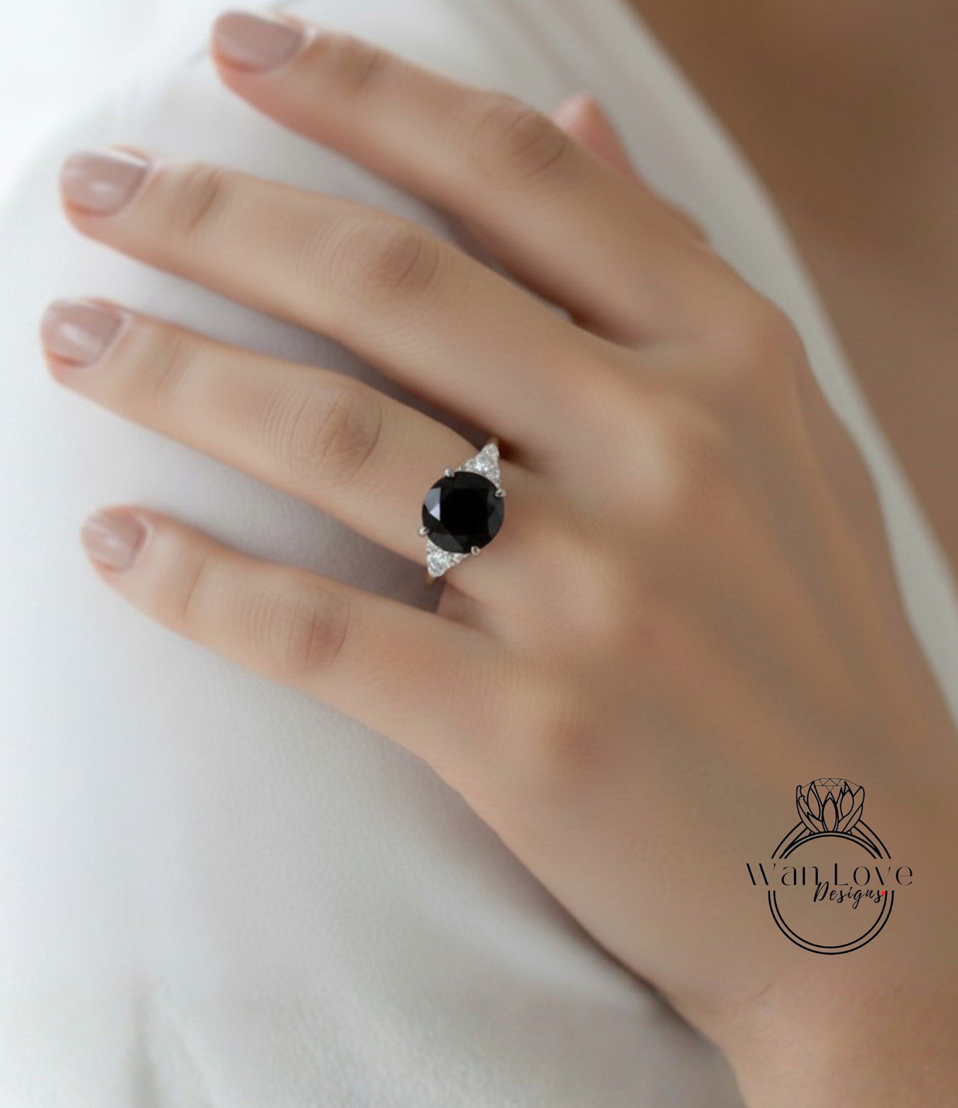 A close-up of a hand wearing a diamond engagement ring with a large black gemstone.