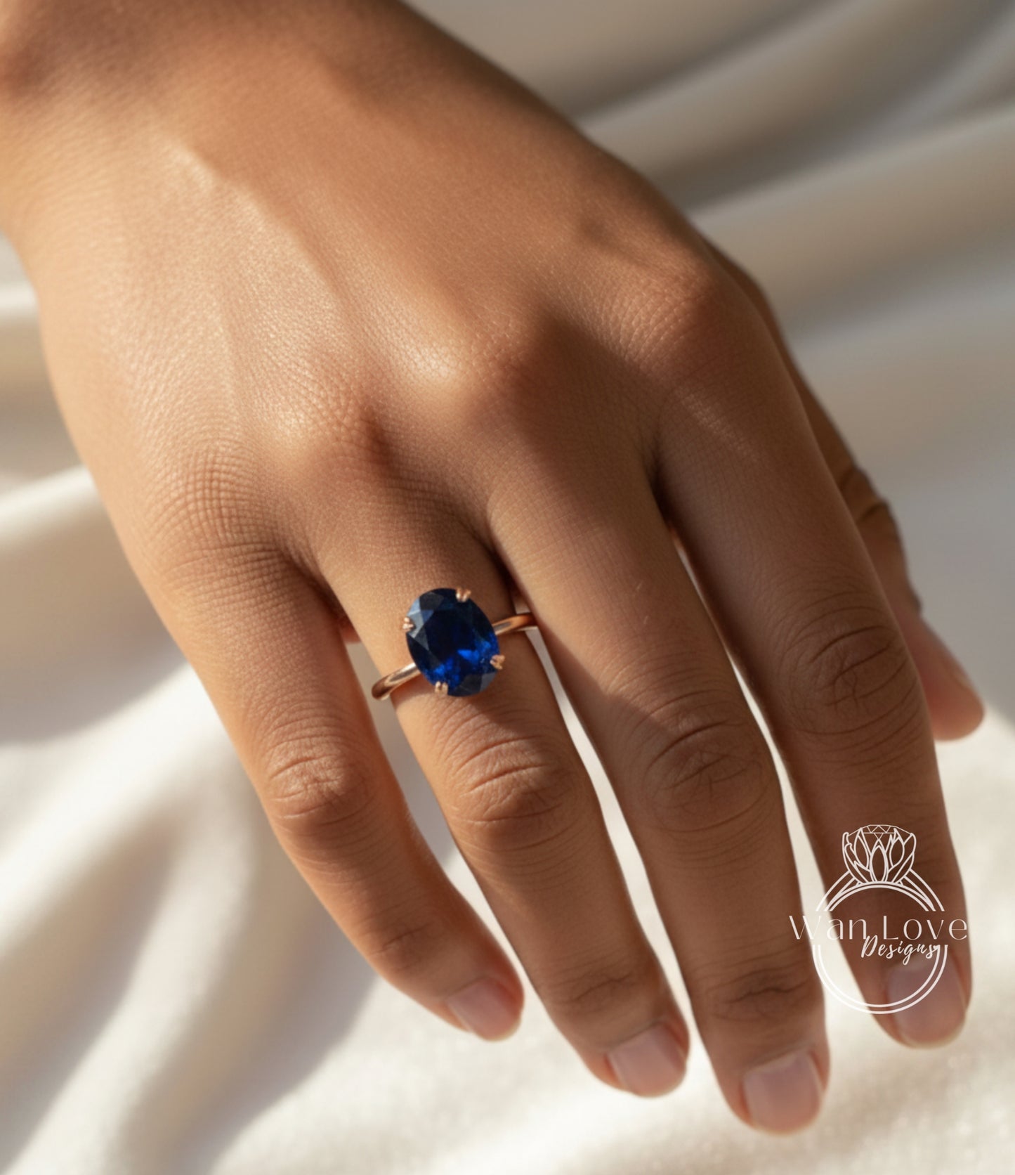A close-up of a hand wearing a ring with a large blue gemstone.
