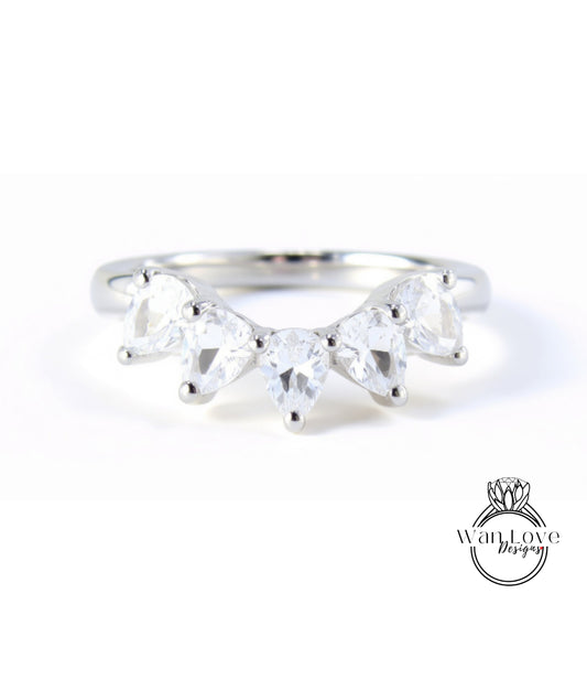 A silver ring with a unique design featuring a row of clear gemstones, likely pear-shaped, set in a band.