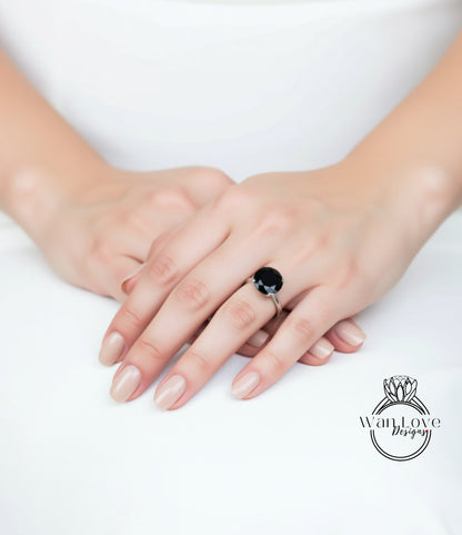 A close-up image of a person's hands wearing a ring with a large black gemstone.