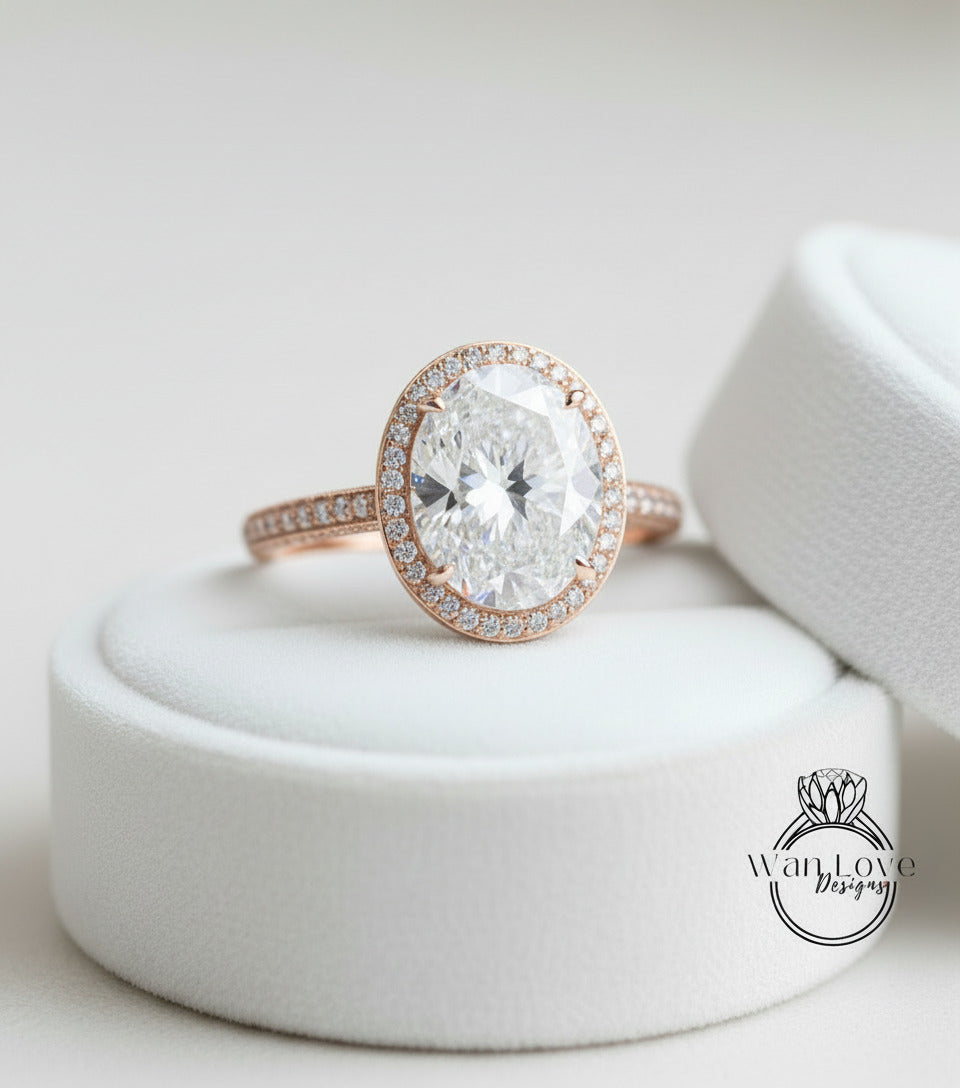 A large, round diamond engagement ring with a halo of smaller diamonds around the center stone, placed on a white pedestal.