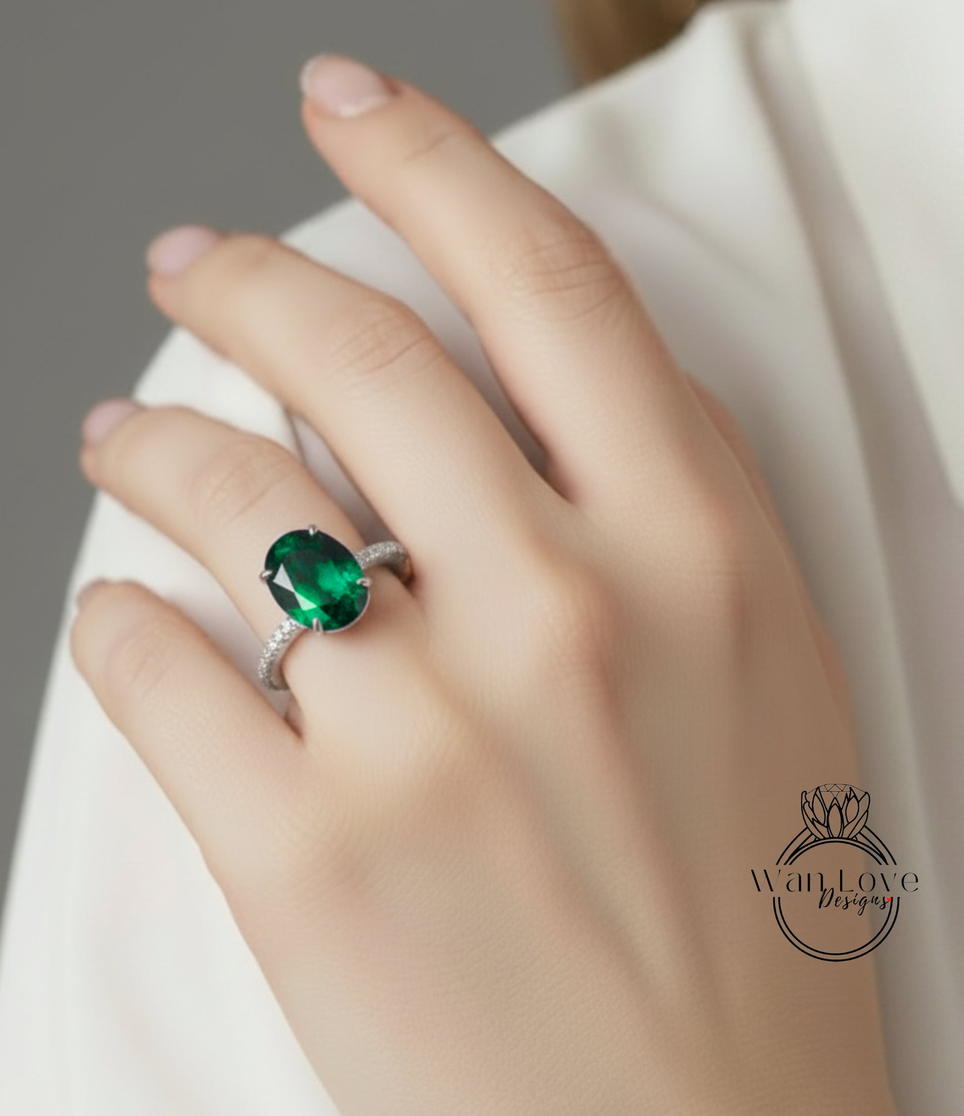 A close-up of a person's hand wearing a ring with a large oval-shaped green gemstone.