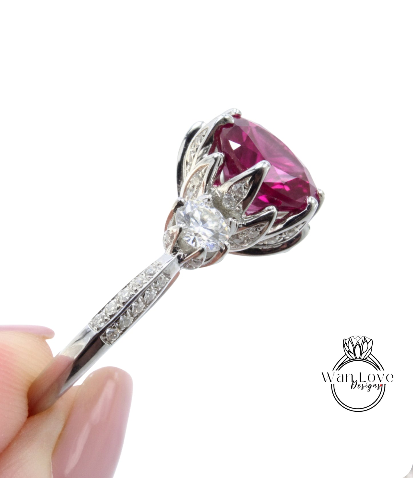 A close-up image of a person's hand holding a silver ring with a large, vibrant red gemstone, likely a diamond, at the center.