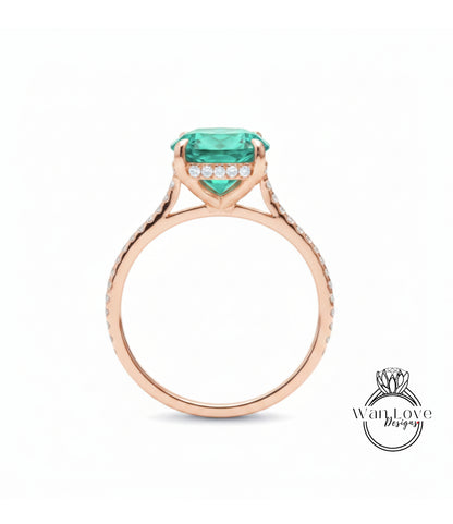 A rose gold engagement ring with a large, vibrant green gemstone set in the center, surrounded by smaller diamonds.