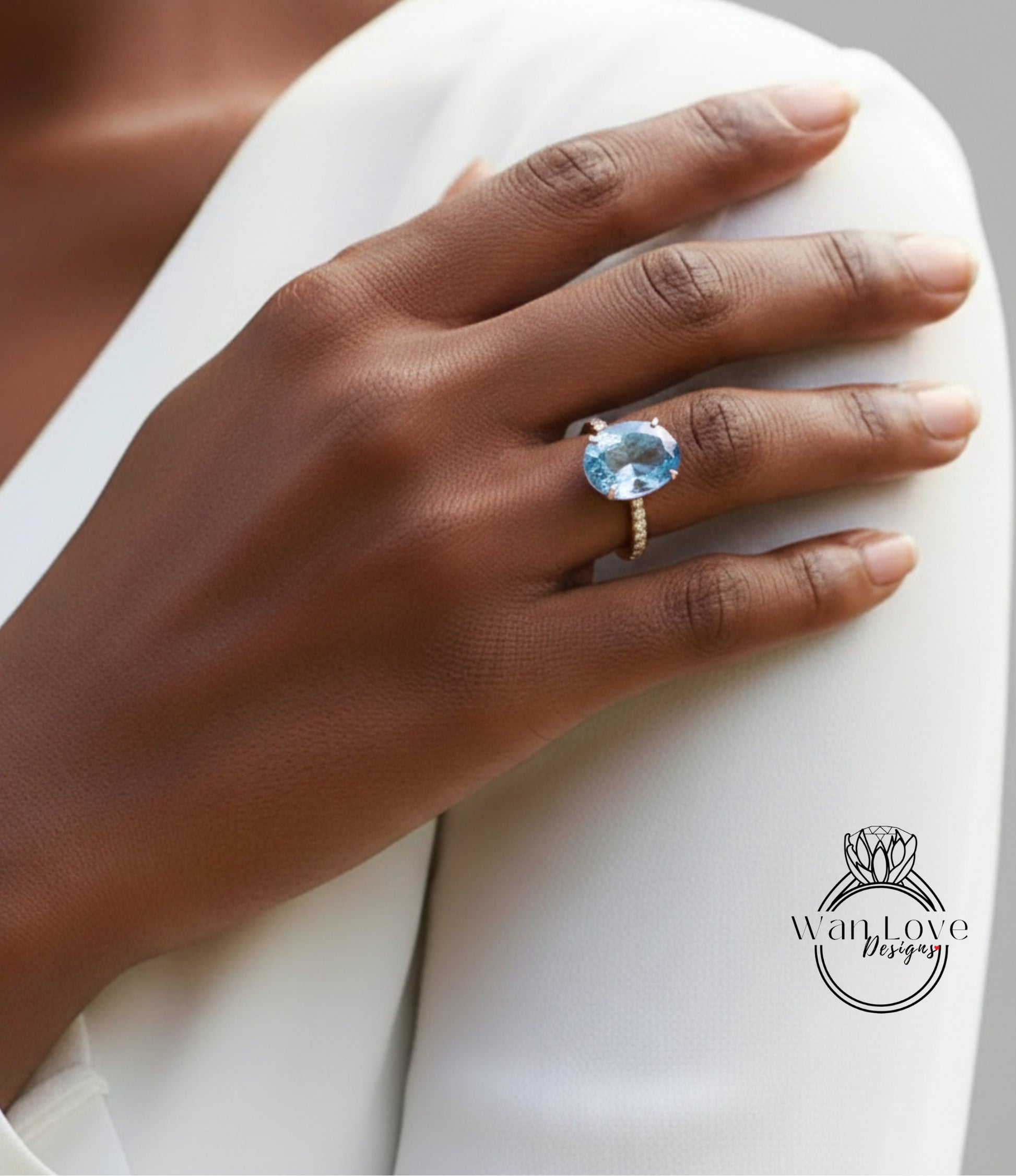 A close-up of a person's hand wearing a large blue gemstone ring on the ring finger.