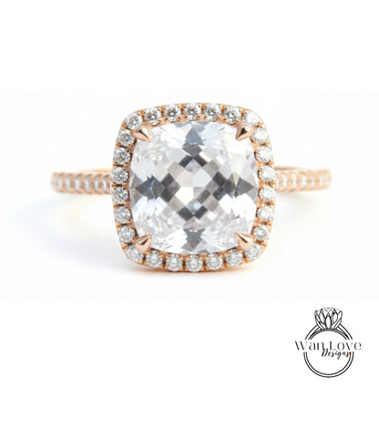 A large, clear gemstone ring with a halo of smaller diamonds around the center stone.