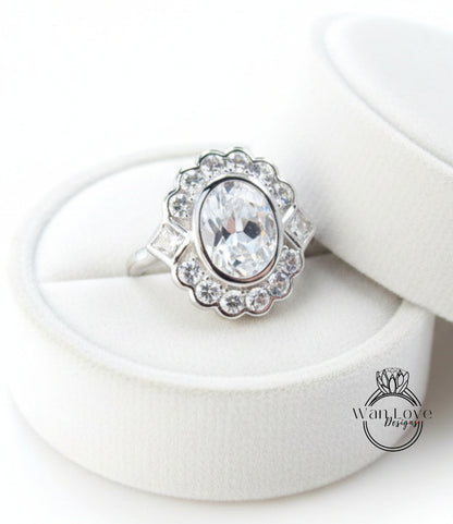 A white diamond ring with a large oval-shaped diamond at the center, surrounded by smaller diamonds, displayed in a white jewelry box.