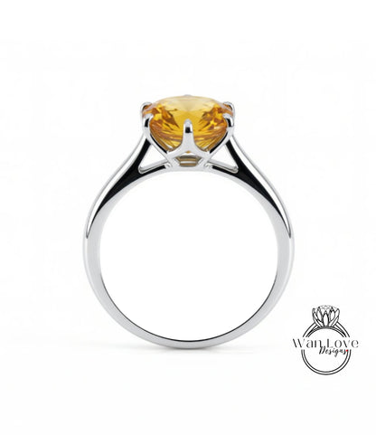 A silver ring with a large yellow gemstone, likely a diamond, set in the center.