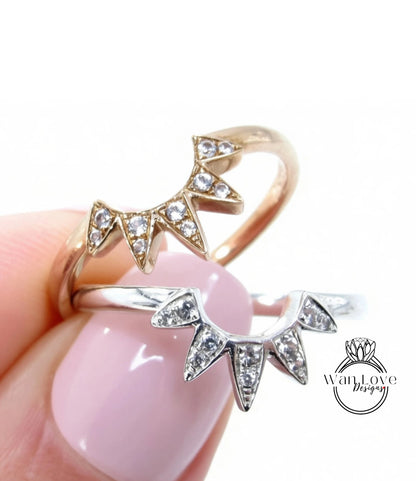 A close-up of a person's hand holding two rings with diamond-encrusted designs.