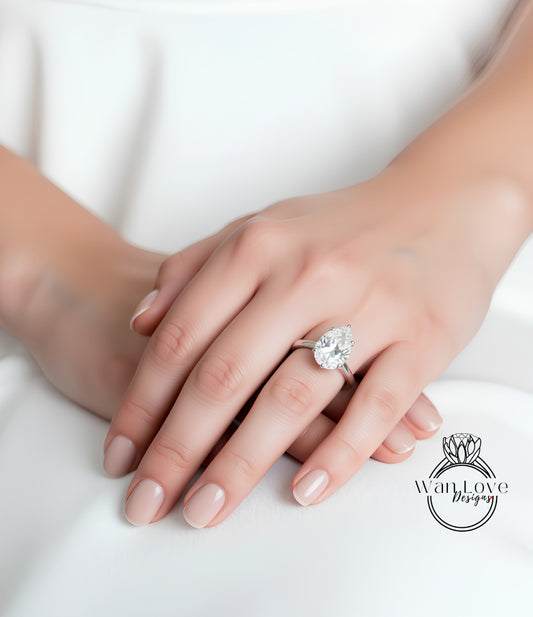 A close-up of a person's hand wearing a large diamond engagement ring.