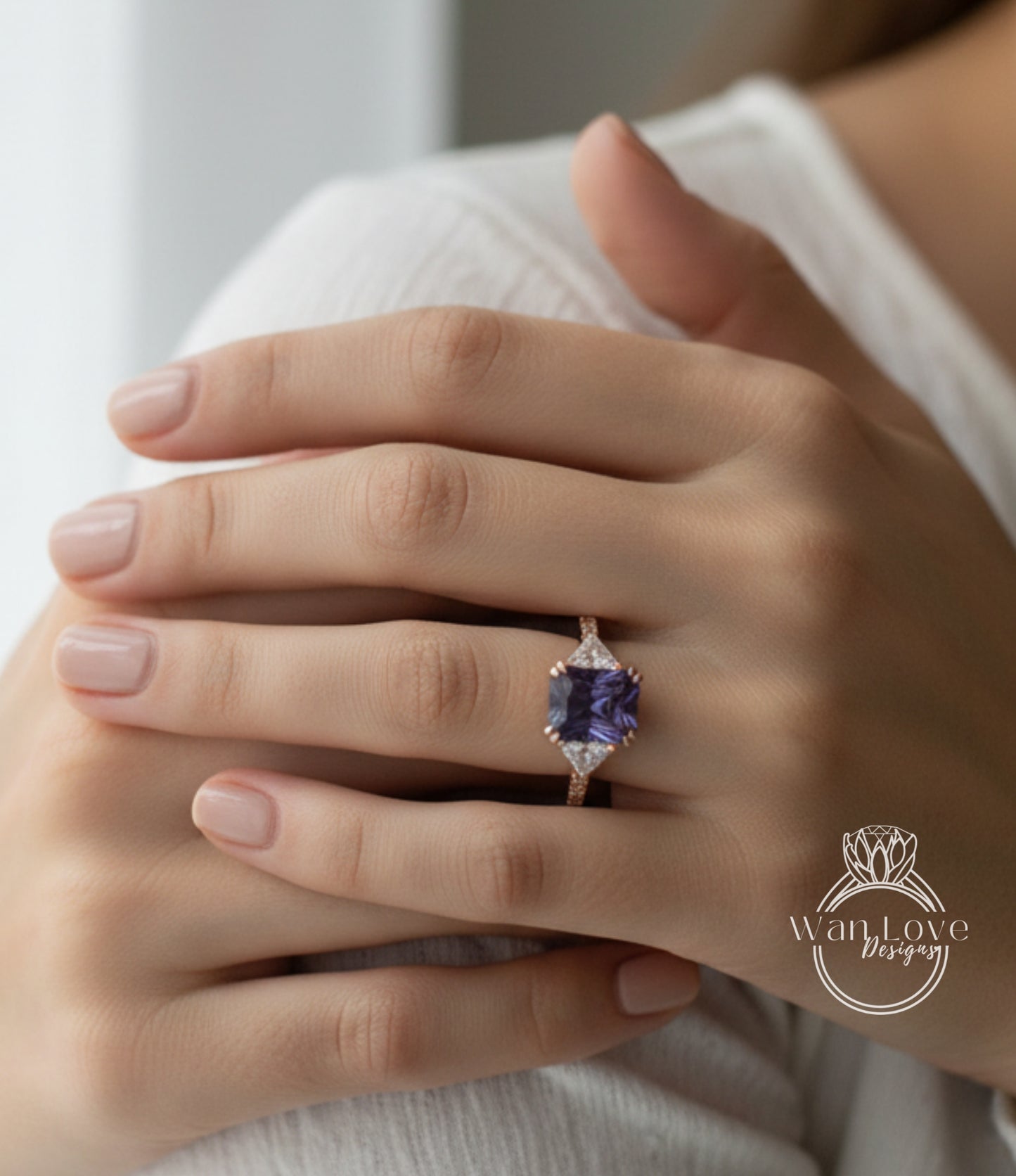 A close-up image of a person's hand wearing a ring with a large purple gemstone.