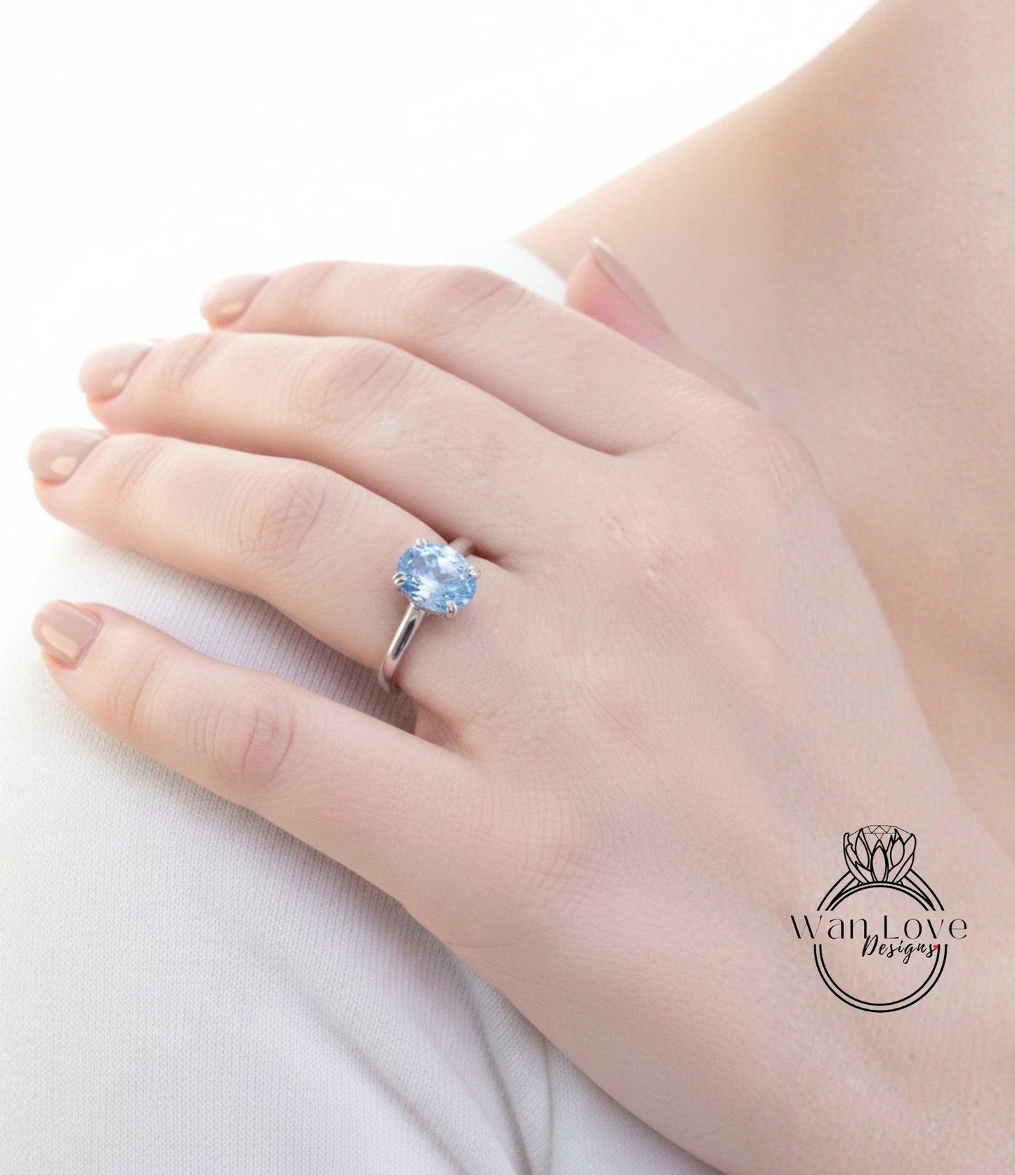 A close-up of a person's hand wearing a ring with a blue gemstone.