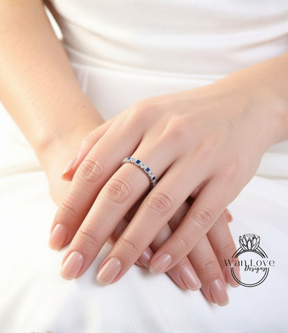 A close-up image of a person's hands wearing a ring with blue gemstones.
