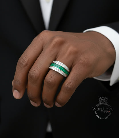 A close-up of a person's hand wearing a ring with a green gemstone band and a diamond band.