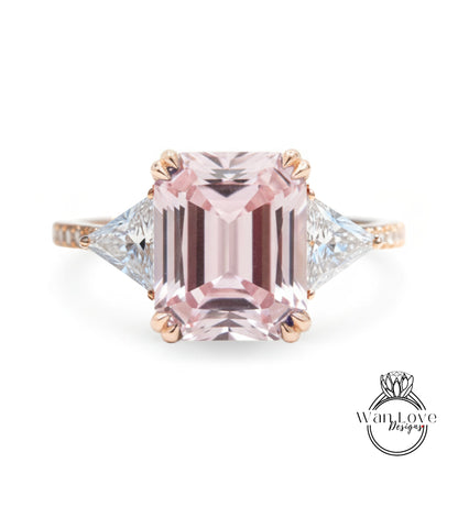 A pink gemstone engagement ring with a large central pink gemstone surrounded by smaller diamonds on either side.