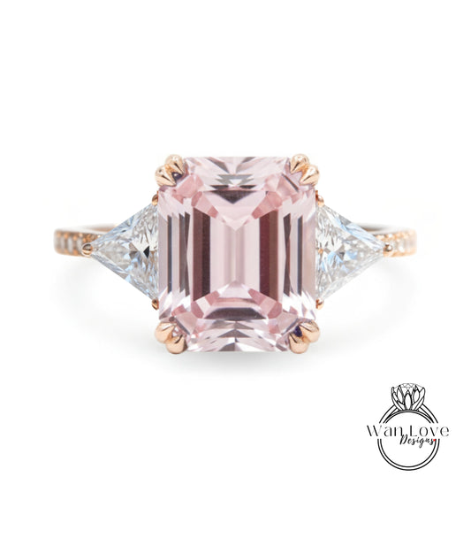 A pink gemstone engagement ring with a large central pink gemstone surrounded by smaller diamonds on either side.
