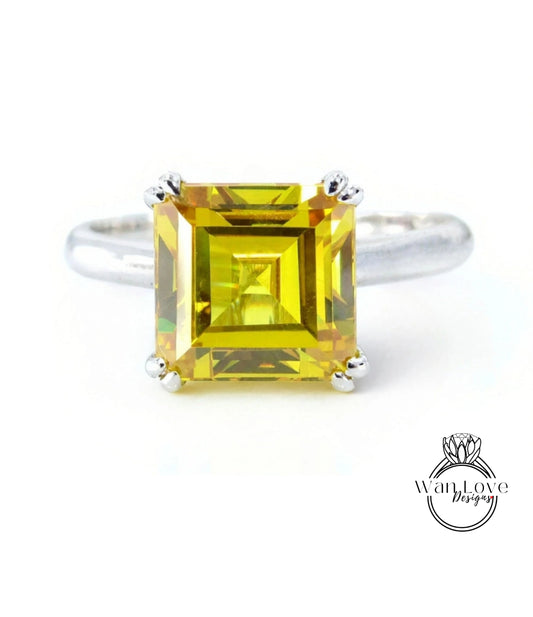 A ring with a large, square yellow gemstone set in a silver band.
