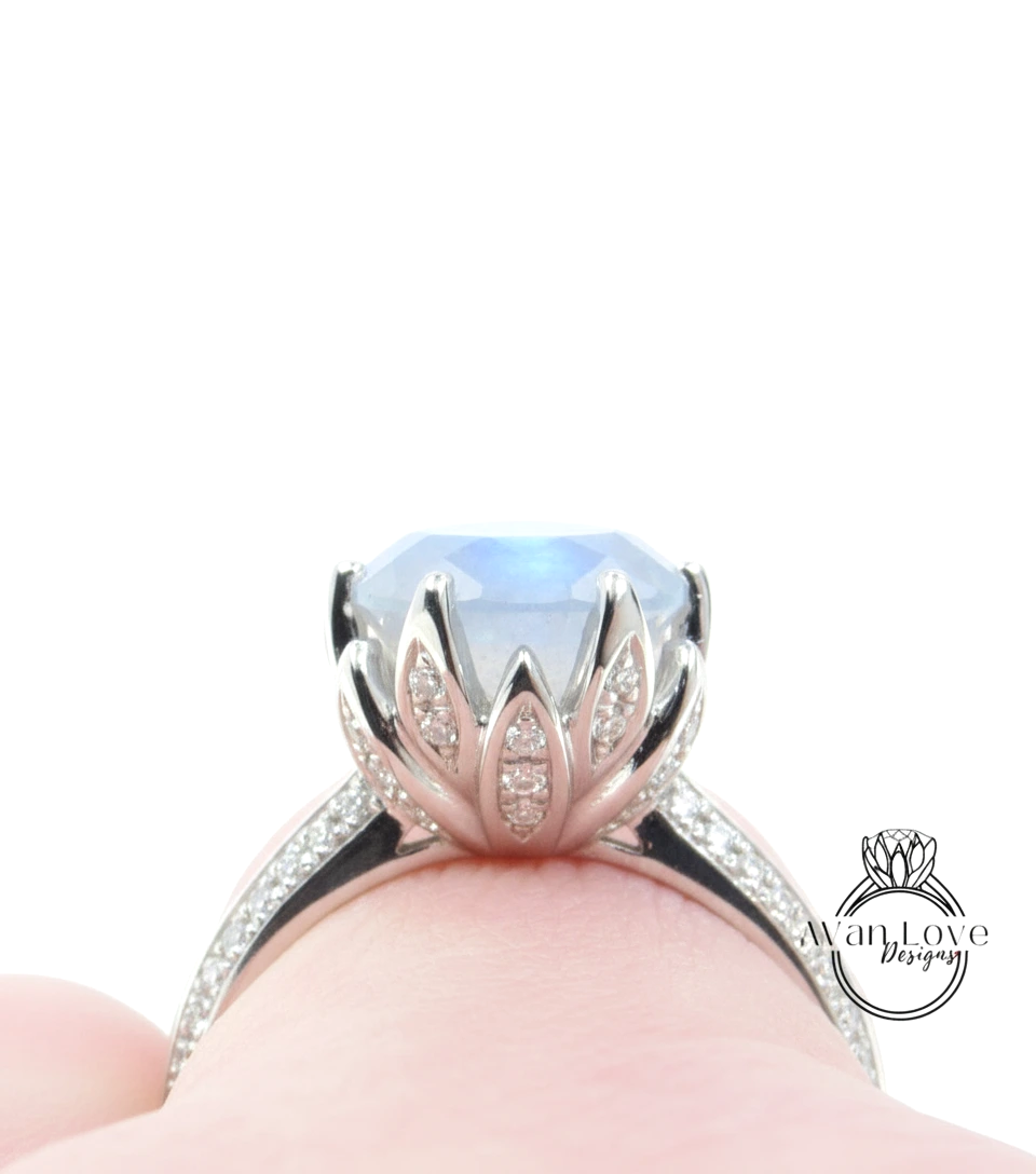 A close-up view of a silver ring with a large blue gemstone, possibly a moonstone, set in a decorative flower-like design.