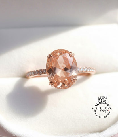 A close-up image of a rose gold engagement ring with a large oval-shaped gemstone set in the center, surrounded by smaller diamonds.