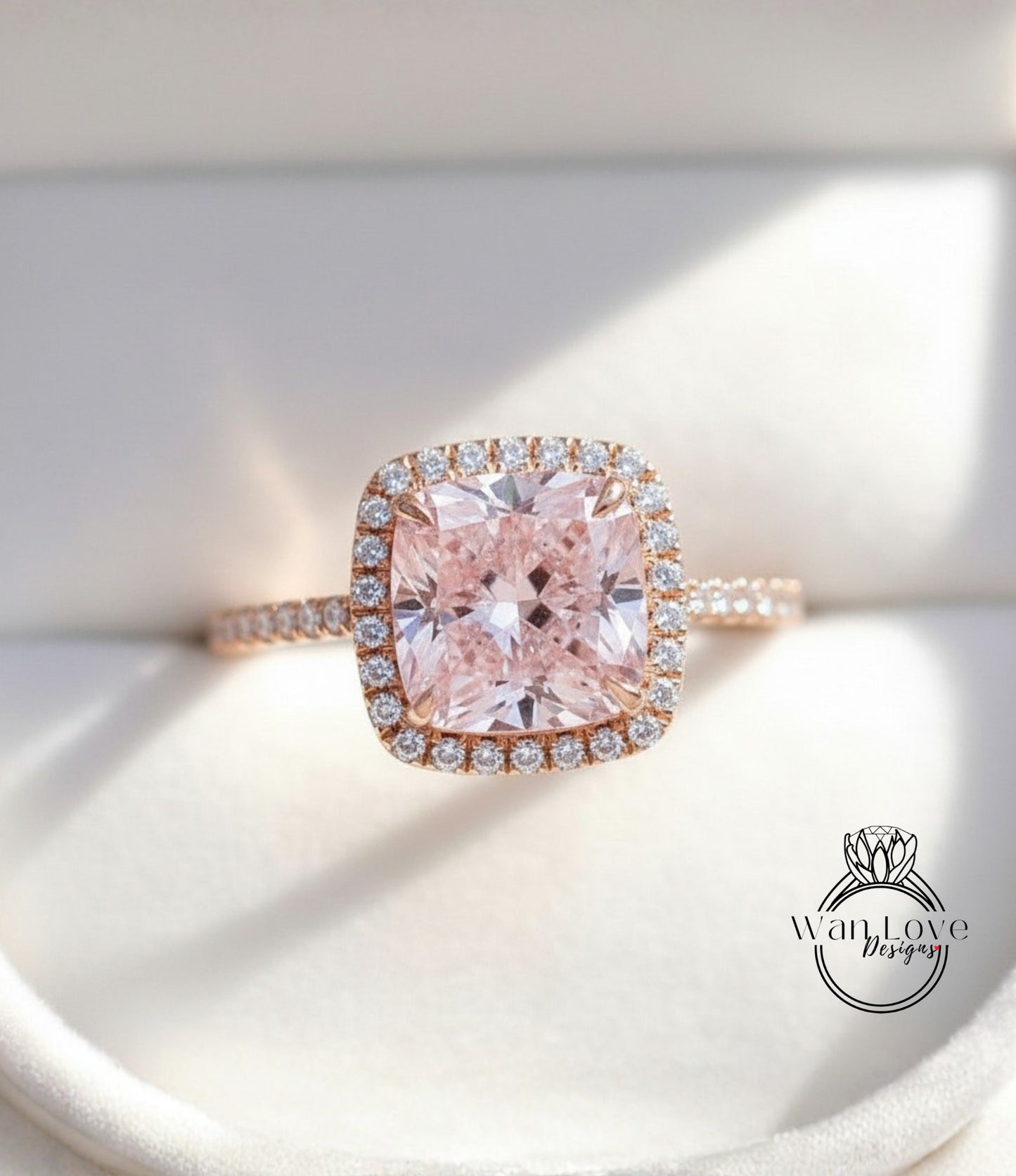 A close-up image of a beautiful pink diamond ring with a halo of smaller diamonds around the center stone.
